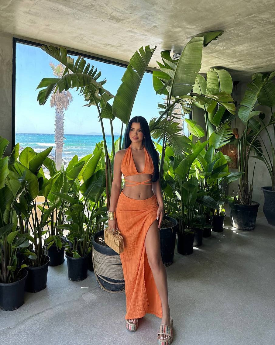 "Model soaking up the sun by the beach in the Tropical Chic Set in orange, embodying the essence of summer vibrancy."
