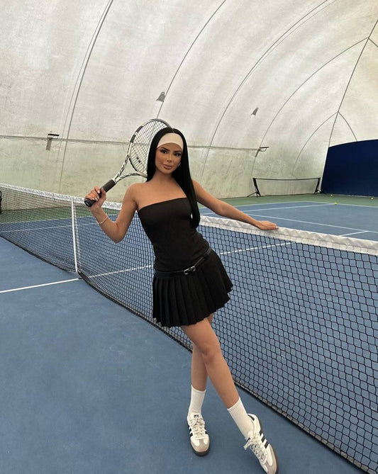 Model playing tennis in the Milan Summer Pleated Dress in black"