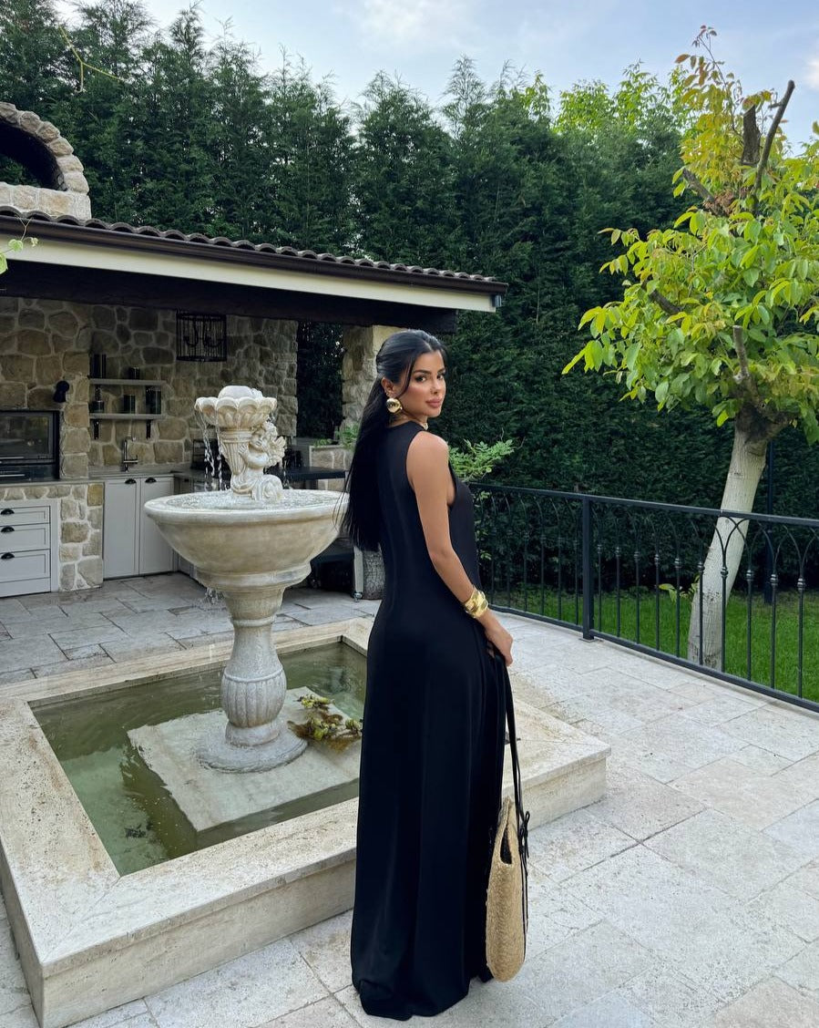 Model wearing the Santorini Breeze Maxi Dress in black by the poolside