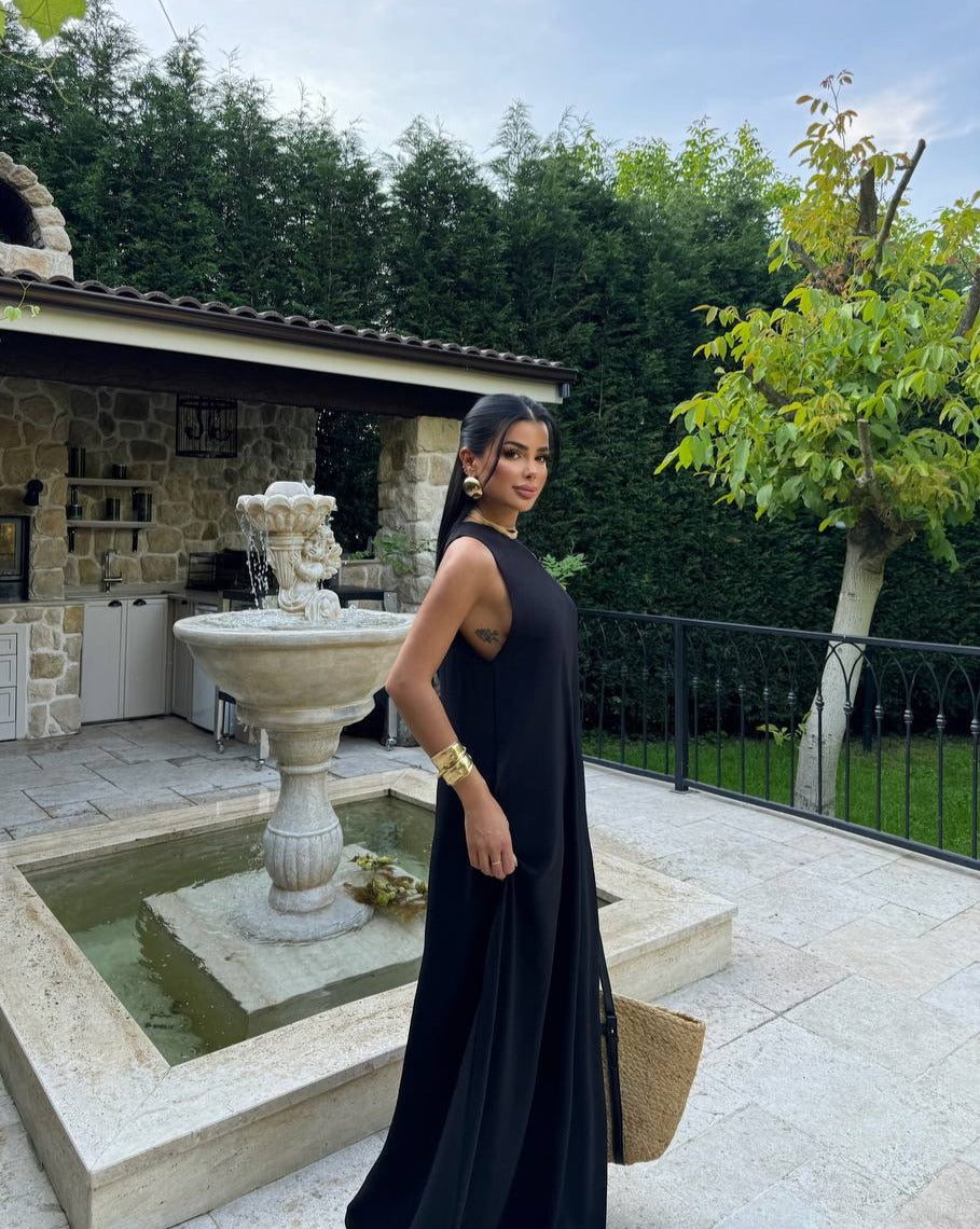 Model wearing the Santorini Breeze Maxi Dress in black by the poolside side view