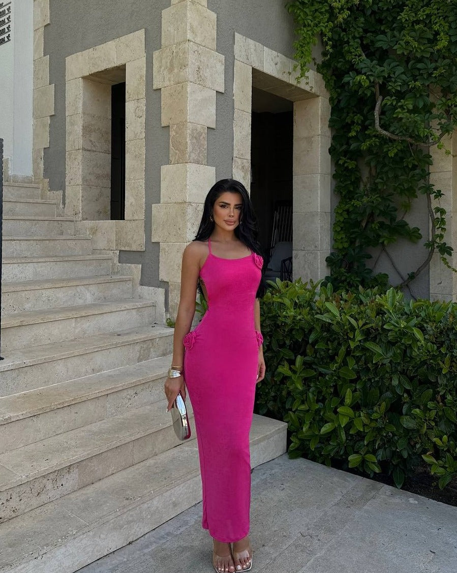 "Model wearing a Riviera Rose Maxi Dress with rose details and rope back detail, standing by stone steps."