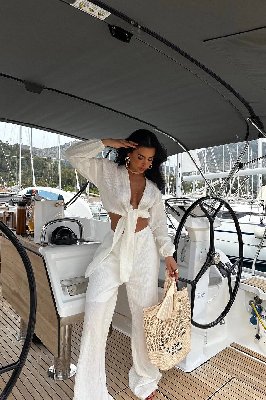 Woman in a white outfit on a boat with a scenic background