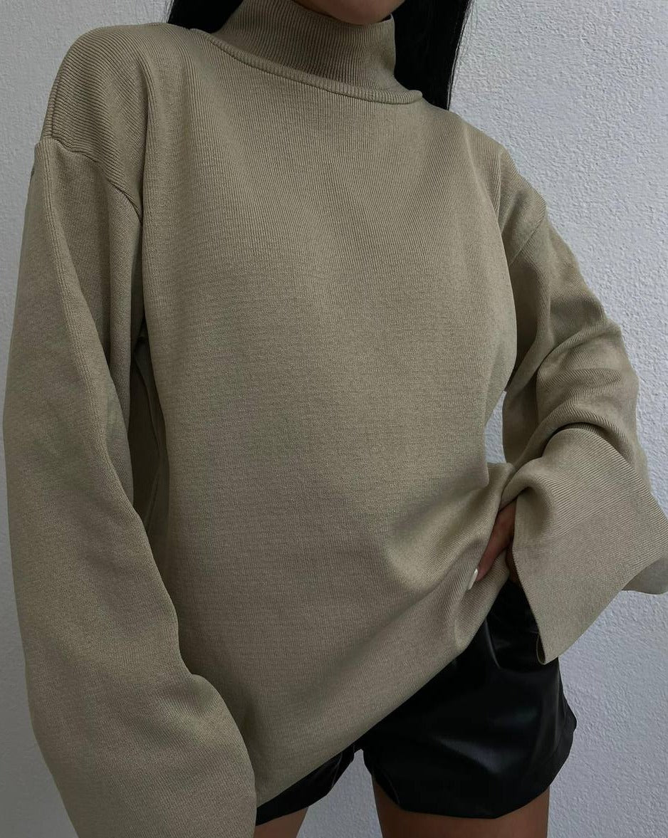 Woman wearing Alice Oversized Turtleneck Sweater in beige, paired with jeans for a cozy and chic look