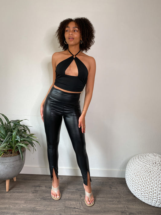 Model wearing the Ava Black Faux Leather Pants, showcasing the wide band high waist and front seam cutout with slit hem.