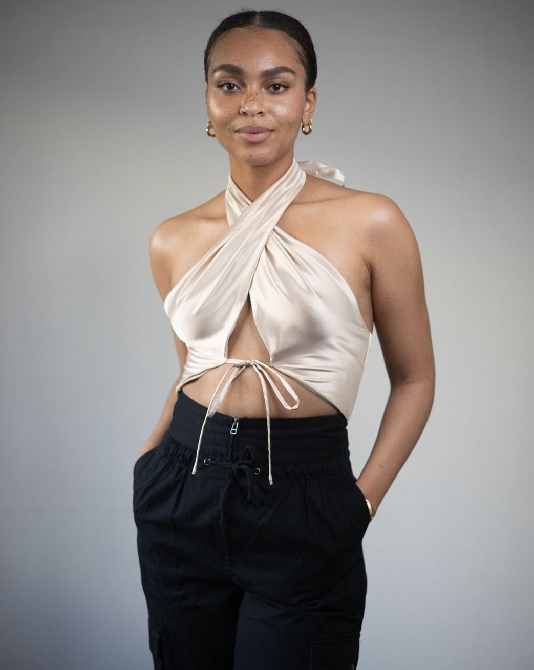 Model wearing the Anastasia Satin Champagne Halter Neck Tie Crop Top, showcasing the elegant tie detail and cross front design.