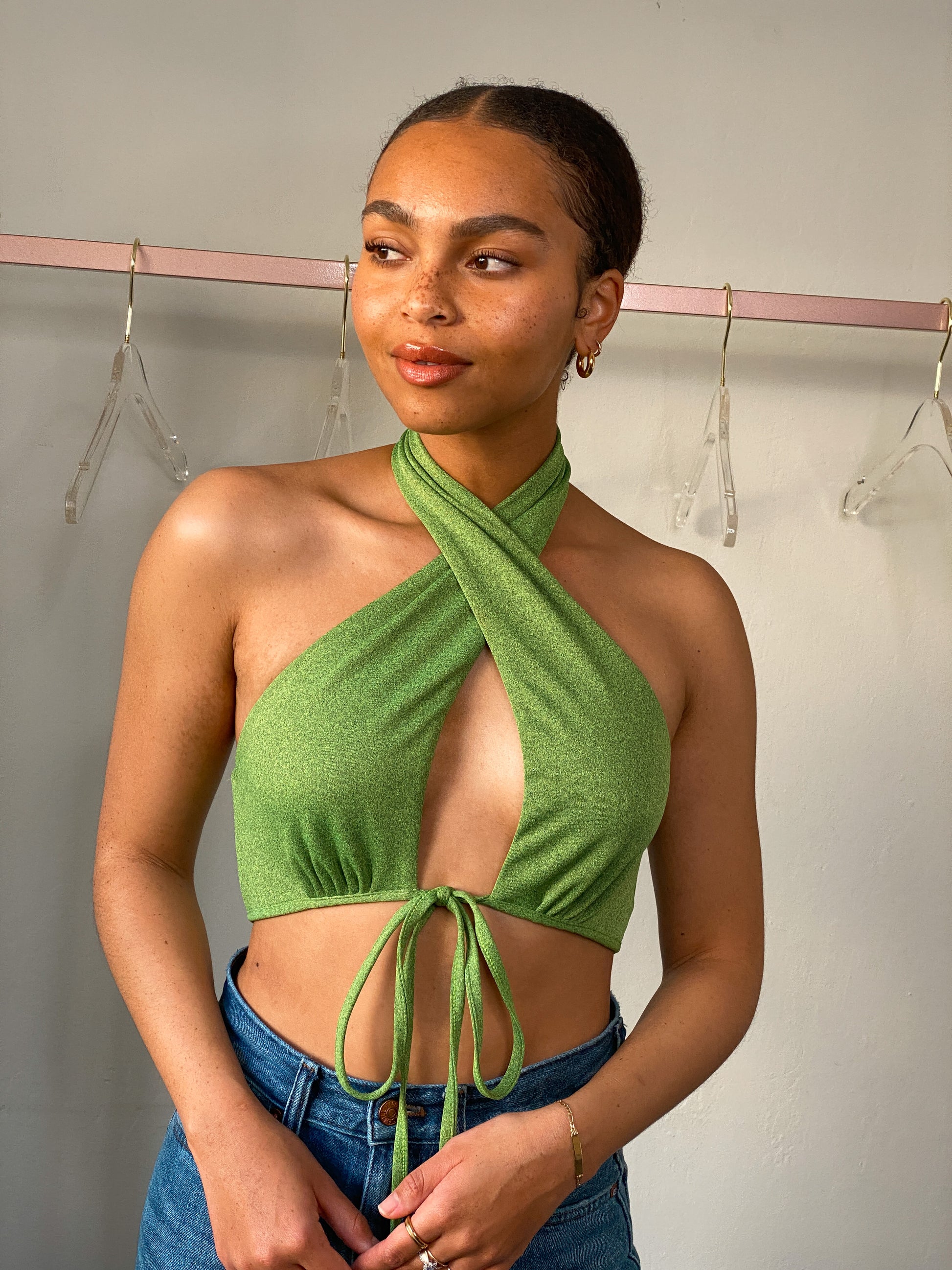 Model wearing the Suki Green Halter Neck Crop Top, showcasing the halter neck, open bust, tie front, and low back detail.