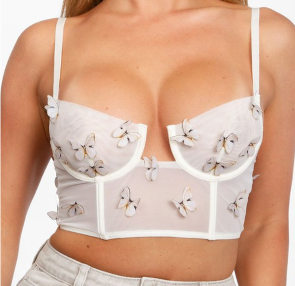 Close-up of 3D butterfly applique detail on white mesh crop top